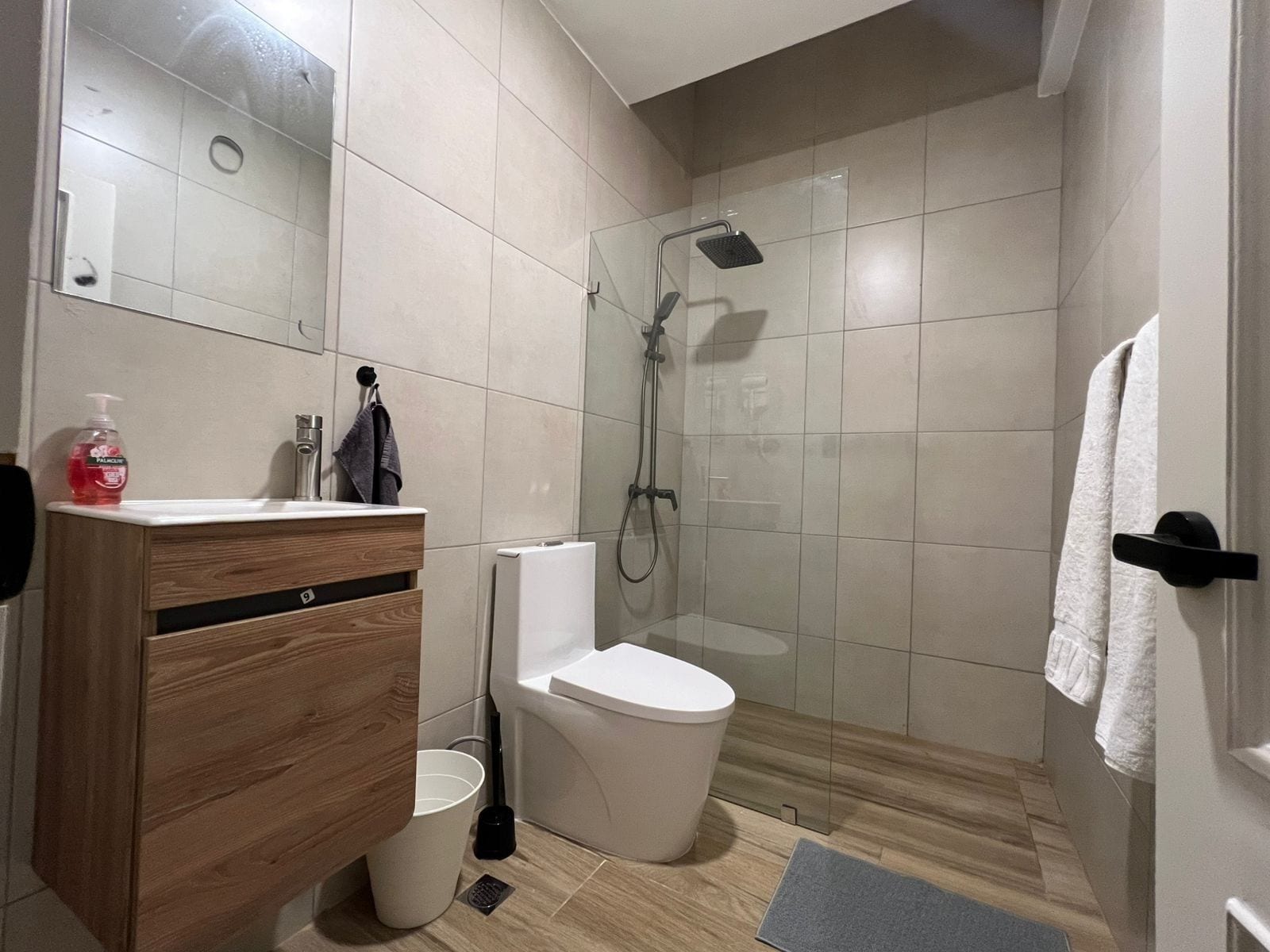 A modern bathroom with a shower, toilet, and vanity.