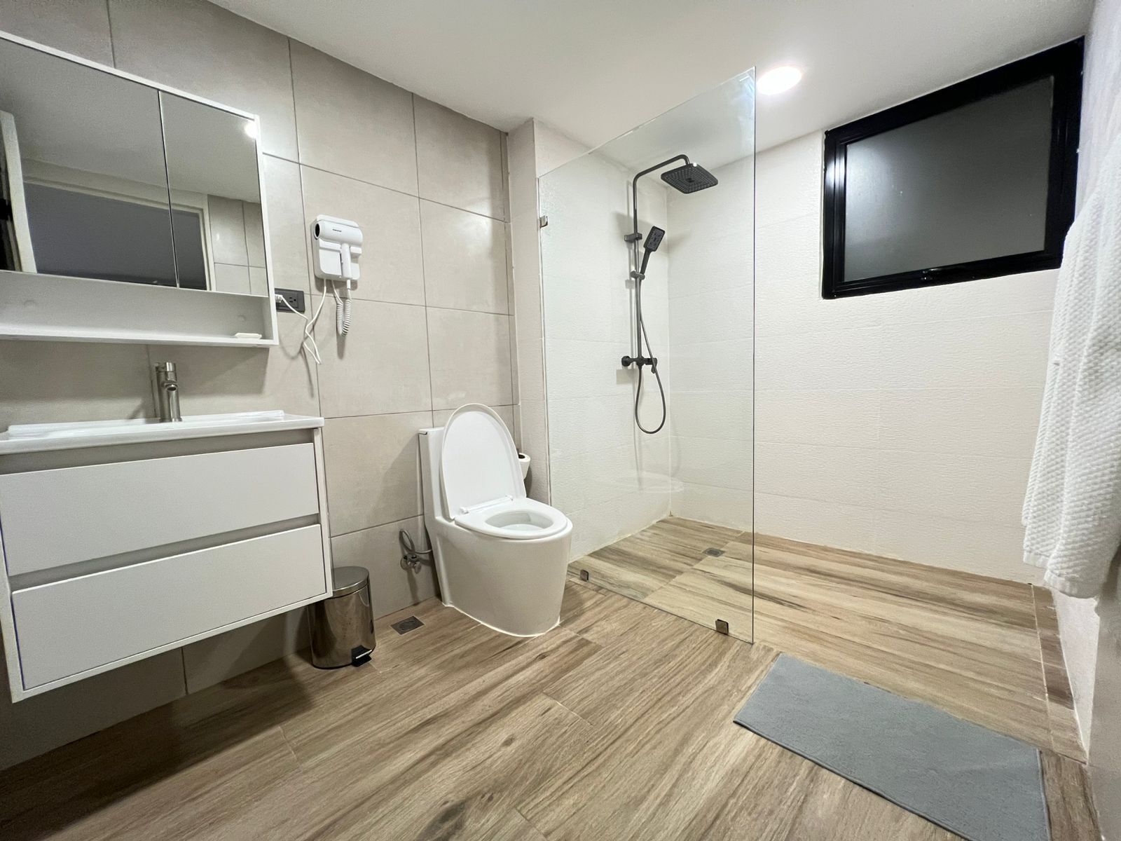 A modern bathroom with a toilet, vanity, and a shower.