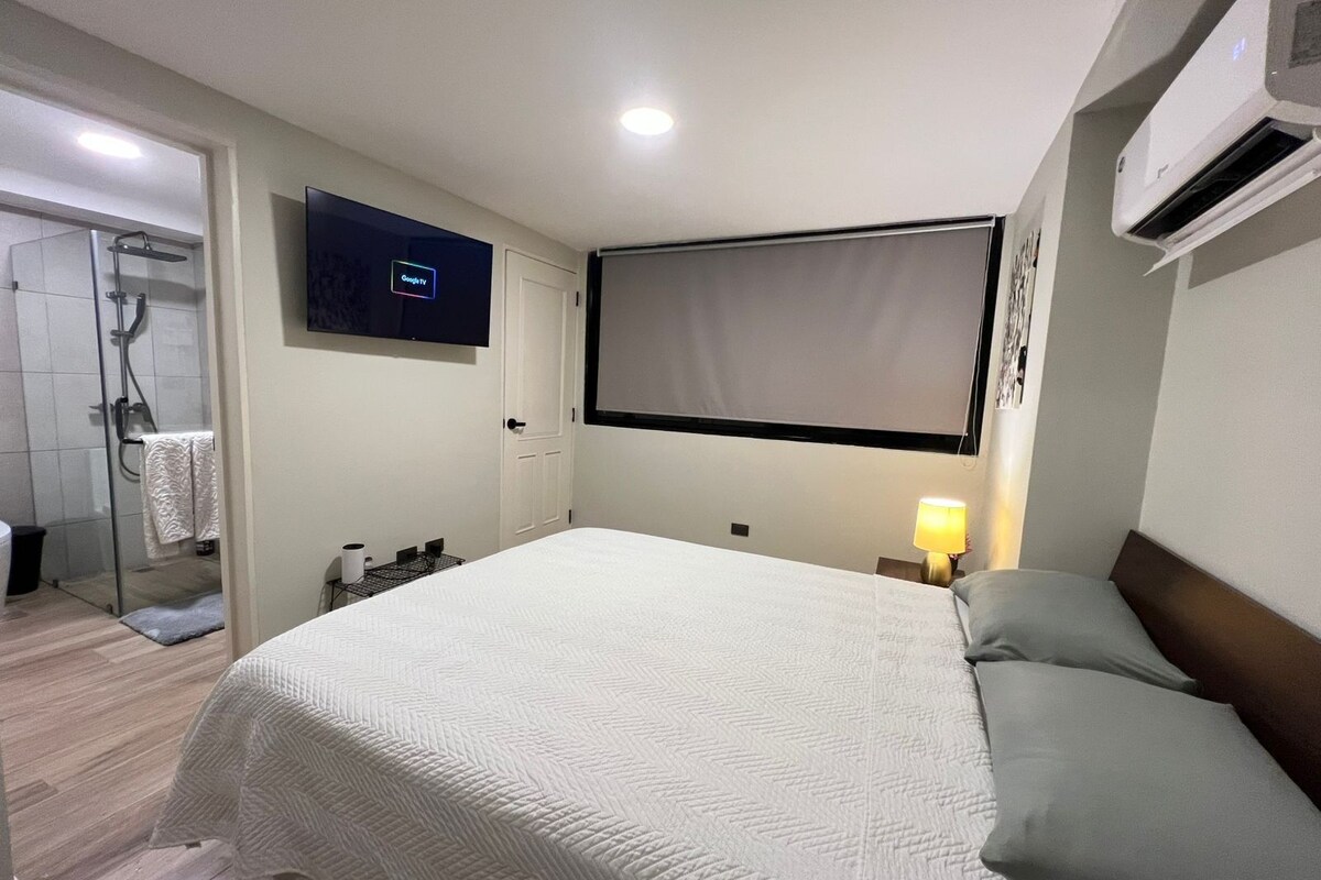 Ein Hotelzimmer mit Bett, Fernseher, Klimaanlage und einer Dusche.