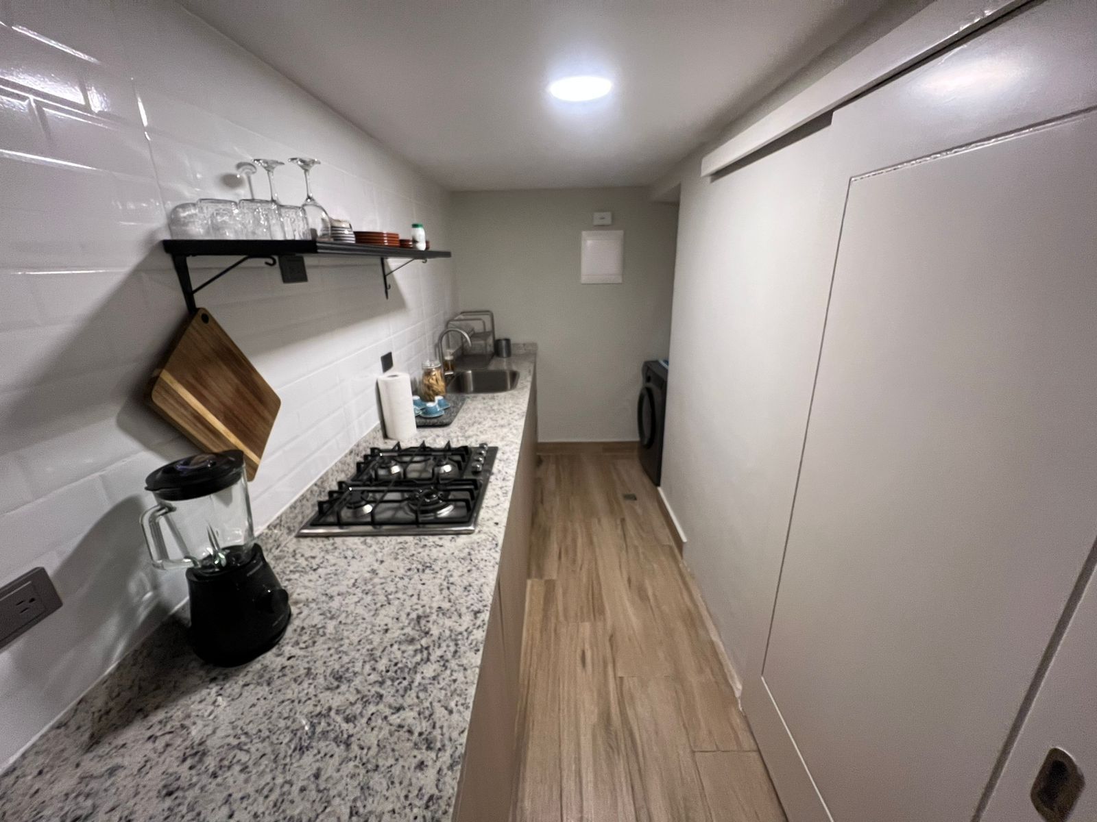 Une cuisine de taille réduite, équipée d’une cuisinière à gaz, d’un évier et d’un plan de travail.