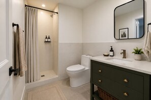 A bathroom with a shower, toilet, vanity with a mirror, and a towel rack. - Spacious Apartment Near Times Square (New York)