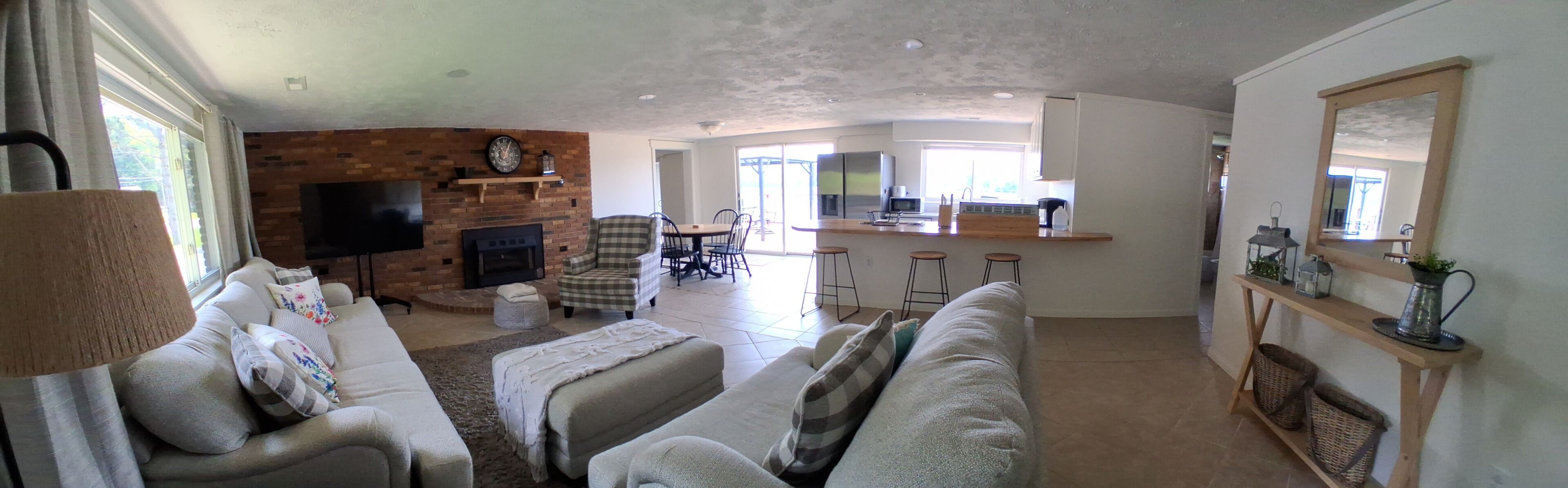 Sala de estar com lareira, televisão e área de jantar com cadeiras e balcão.