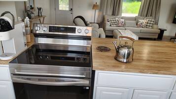 A kitchen with a stainless steel stove, a wooden countertop, and a kettle.