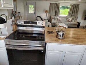 Una cocina con estufa de acero inoxidable, encimera de madera y hervidor.