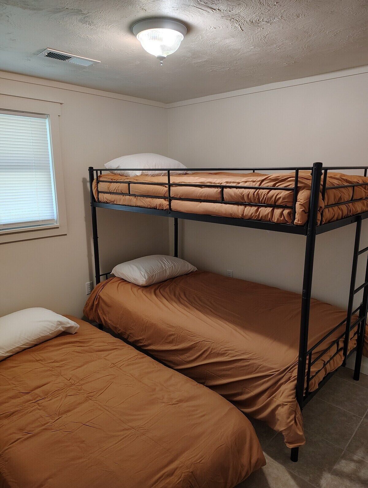 A bunk bed room with a window and a ceiling vent.