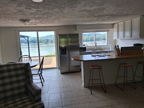 Una cocina con una isla grande, un comedor con sillas y vistas a un lago.