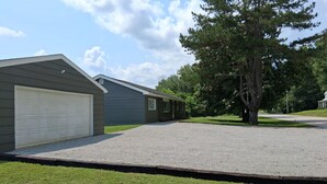 Um imóvel residencial com garagem, varanda coberta e entrada de automóveis que leva a uma casa.