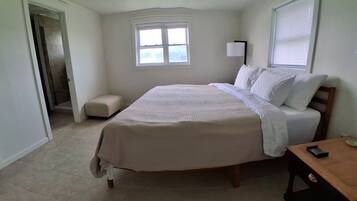 Un dormitorio con una cama, una mesita de noche, una ventana y una puerta.