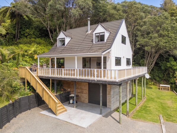 A two-story house with a balcony, a staircase, and a garage. - Skippers View - Onemana Holiday Home (Whangamata)