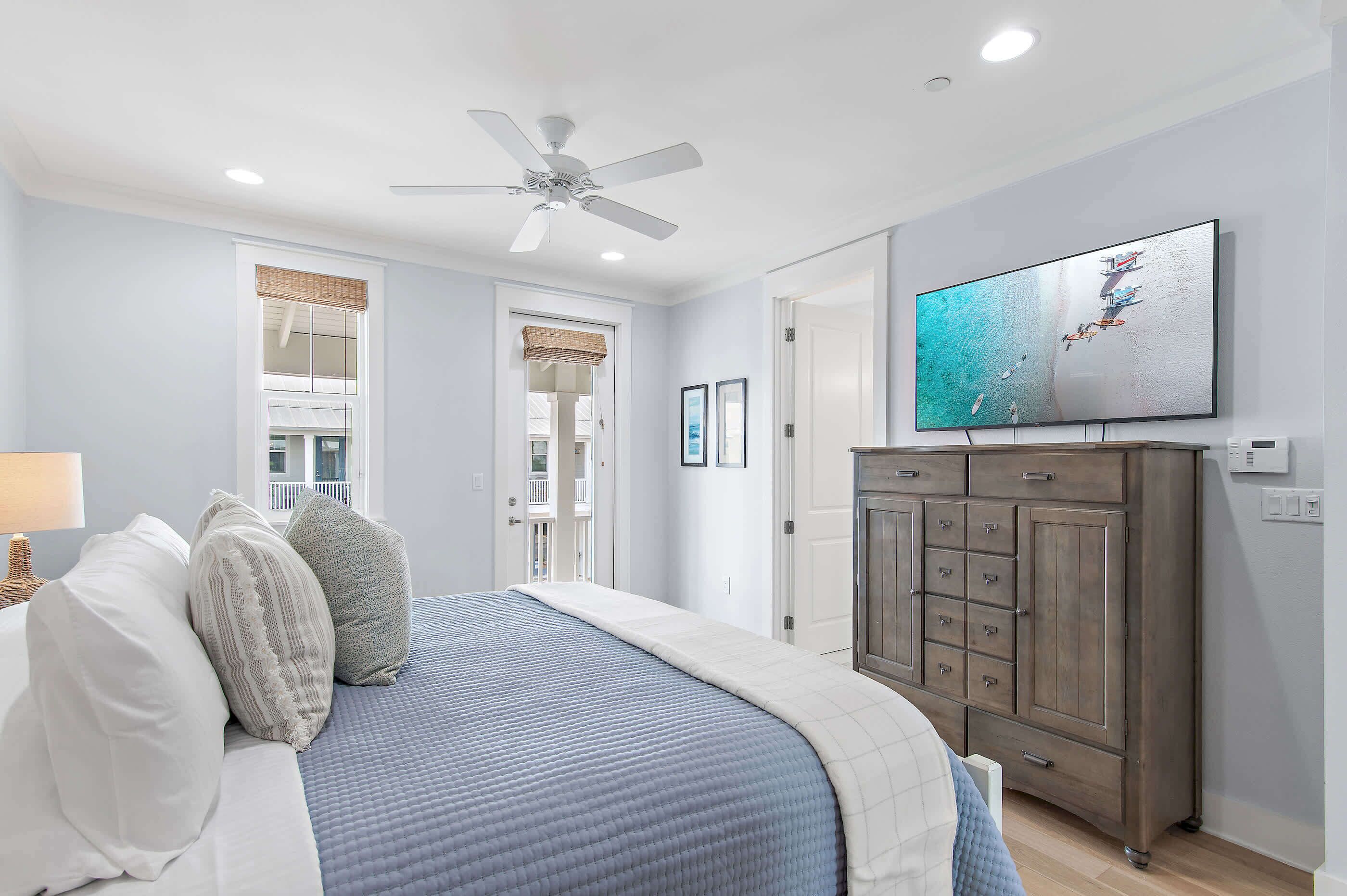 A bedroom with a bed, a ceiling fan, a television, and a wardrobe.