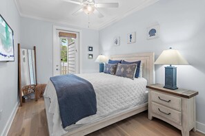 Ein Schlafzimmer mit einem Bett, Nachttischlampen, einem Beistelltisch und einem Deckenventilator.