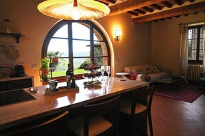 Un comedor con un ventanal grande, una mesa dispuesta con platos, vasos y botellas, y vista a zonas verdes al exterior.