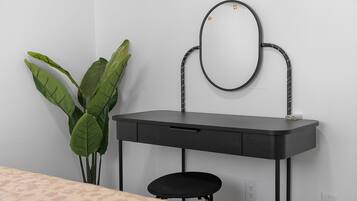 Une pièce avec un bureau noir, un miroir et une plante en pot.