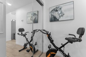 Ein Fitnessraum mit Ergometer, Laufband und Spiegel, der den Raum wiedergibt.