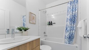 Un baño con bañera, inodoro, lavabo y cortina de ducha.