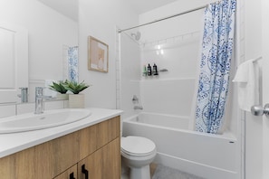 Een badkamer met een bad, toilet, wastafel en douchegordijn.