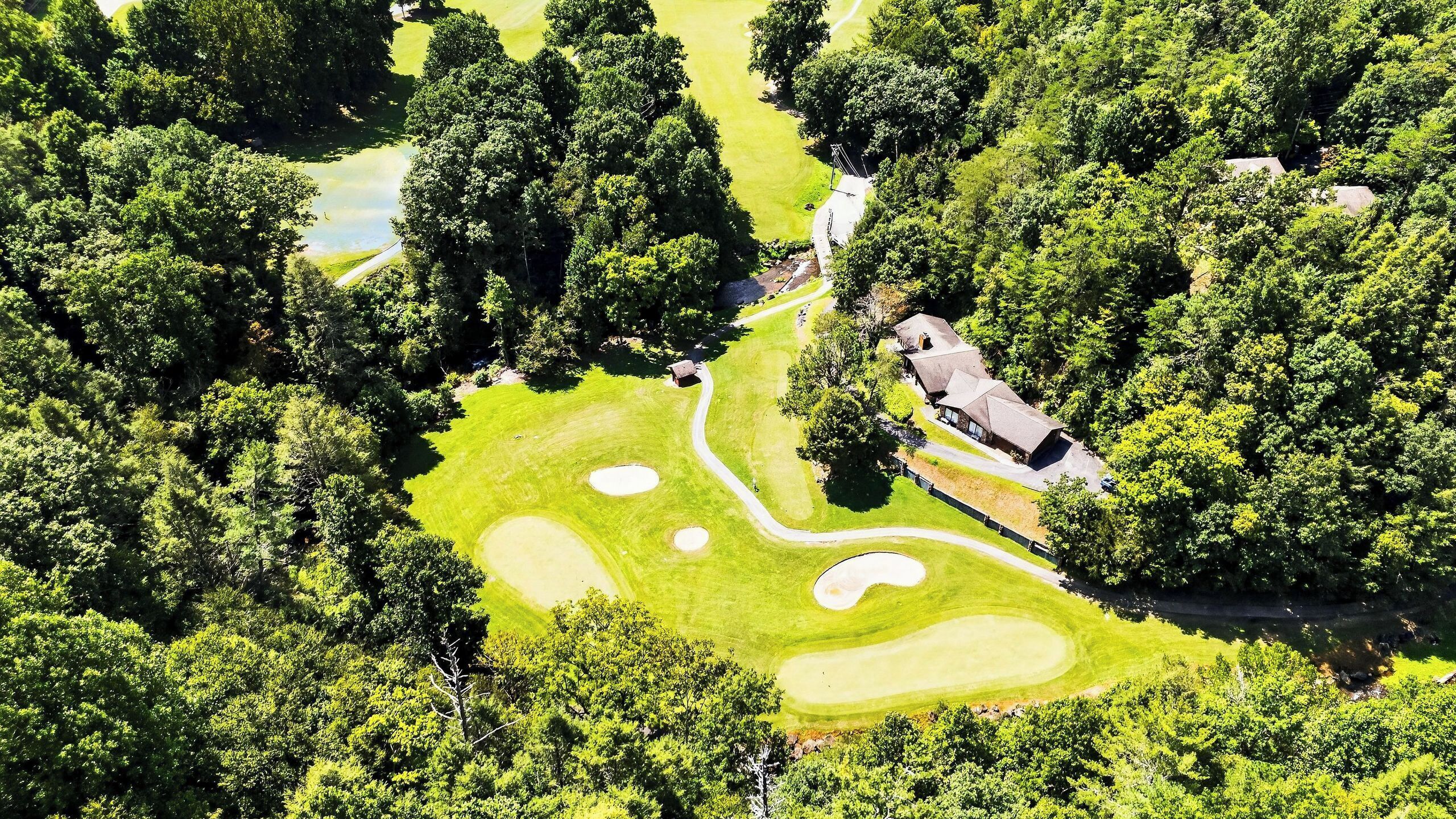 Un campo de golf con un club de campo, rodeado de árboles frondosos.