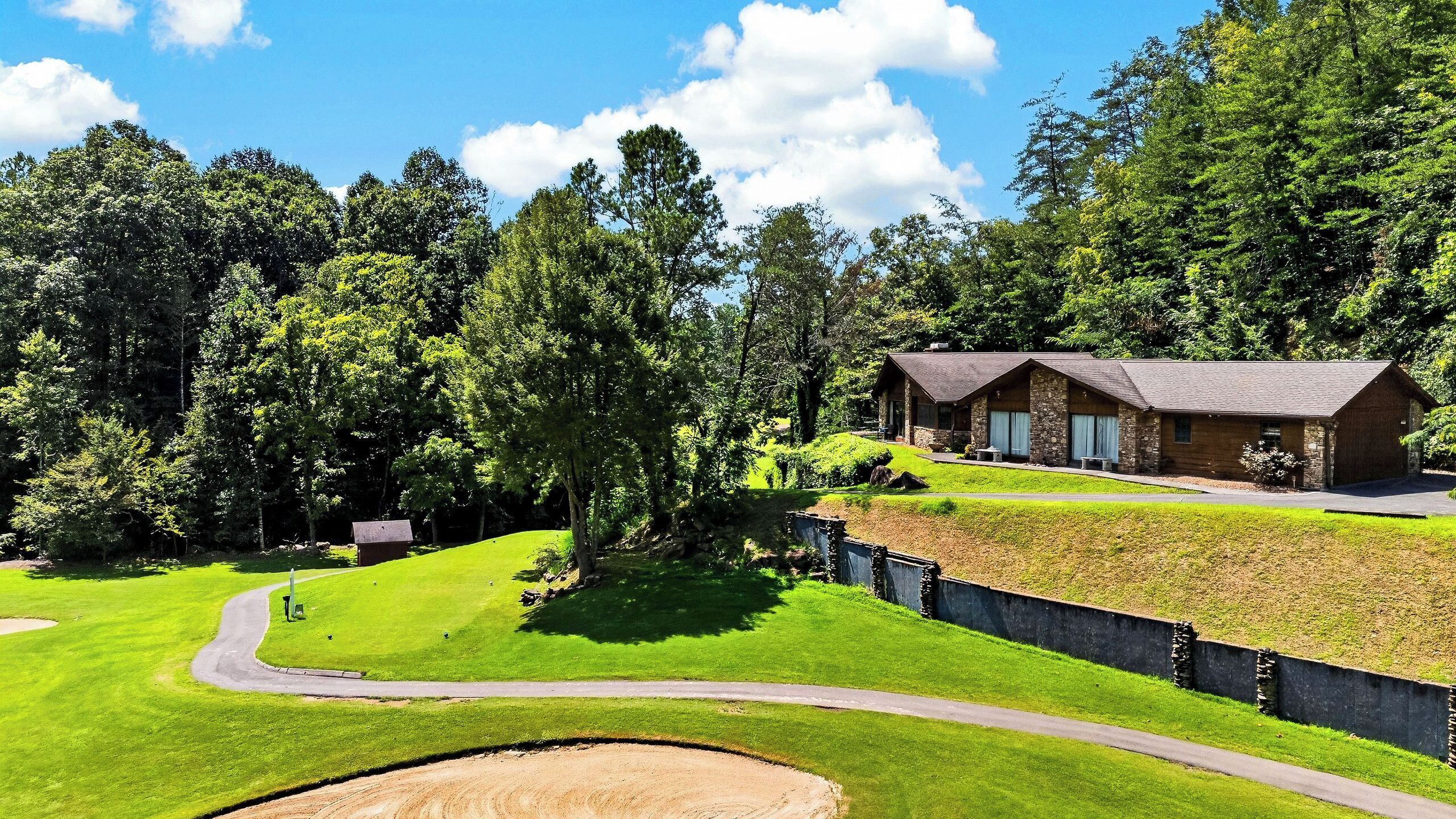 A lodge with a stone exterior, a grassy lawn, and a dirt path leading to the entrance.