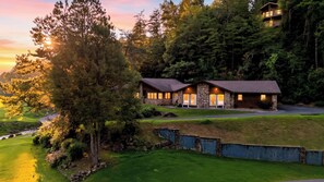 A two-story stone cabin with a stone facade, surrounded by lush greenery and a well-maintained lawn. - Creek & Green by Avantstay Creekside Hot Tub + Pool Table Golf Course Views (Gatlinburg)