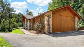 Ein zweistöckiges Holzhaus mit Steinuntergrund, einer großen Garage und einer Auffahrt zum Eingang.