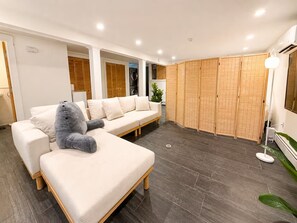 Ein modernes Wohnzimmer mit einer Eckcouch, einem grauen Sessel und Holzboden.