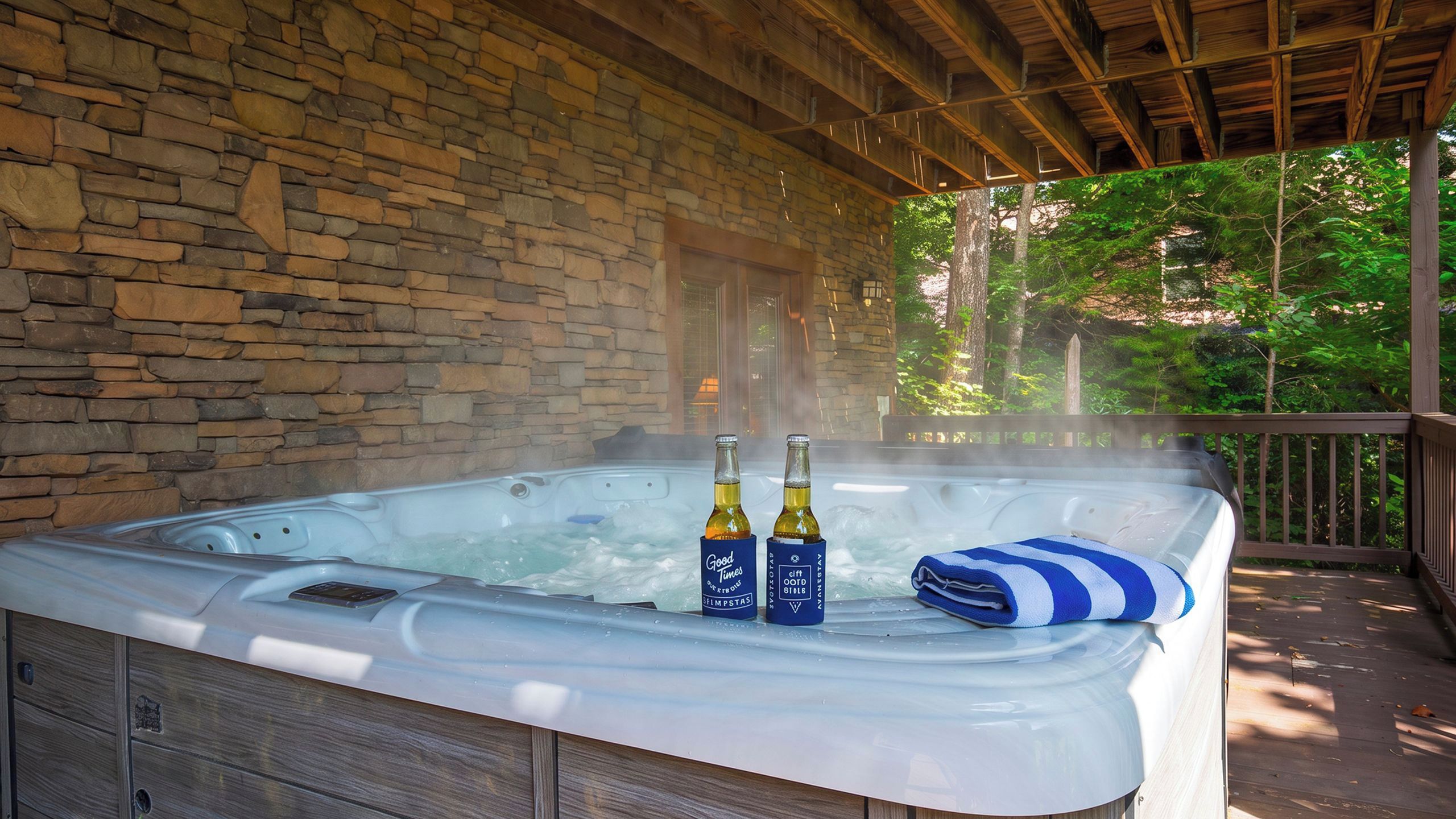 Un jacuzzi con dos botellas de alcohol, una toalla y un muro de piedra al fondo.