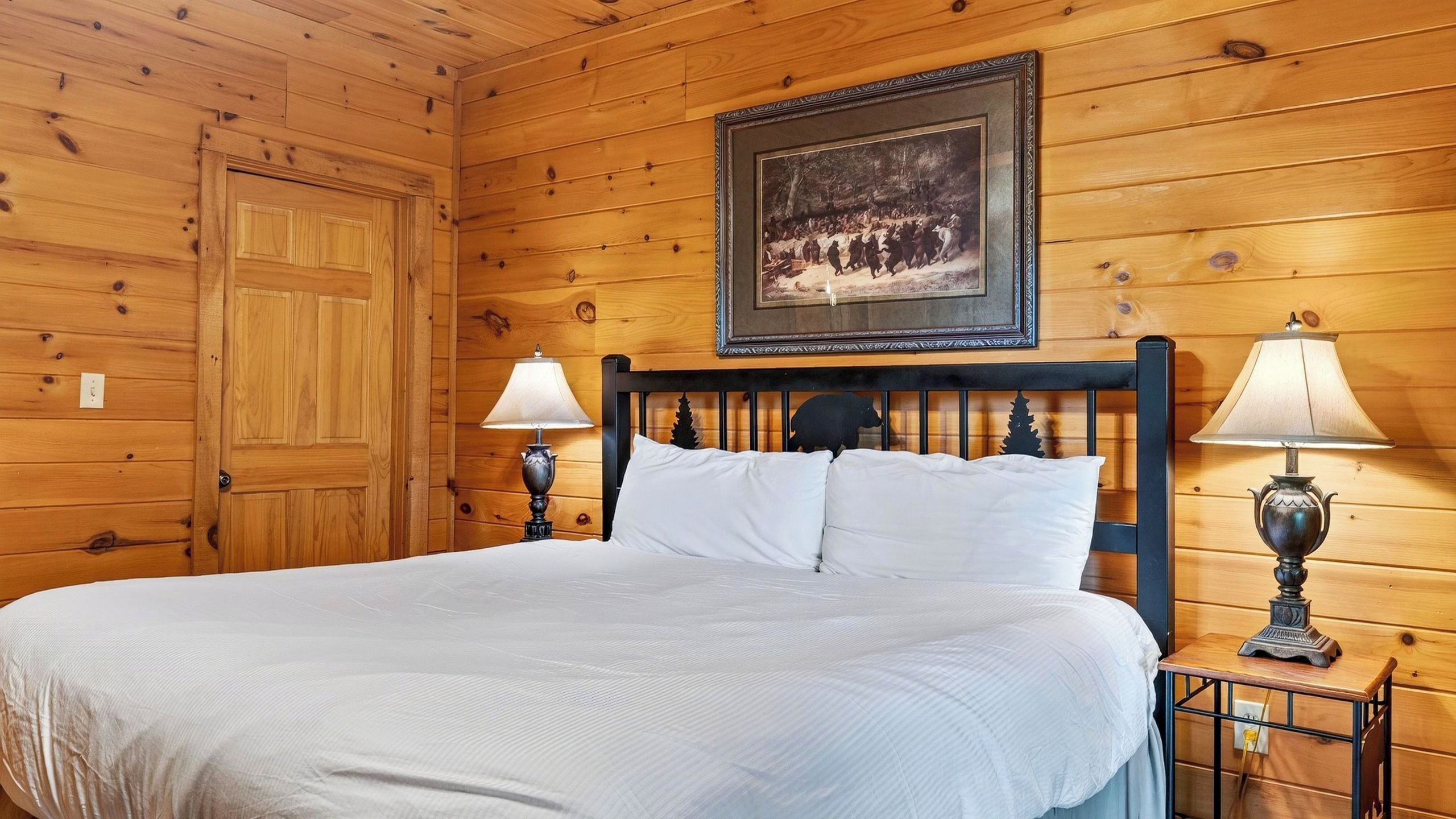 Una habitación con paneles de madera, una cama, dos lámparas de noche y un cuadro en la pared.