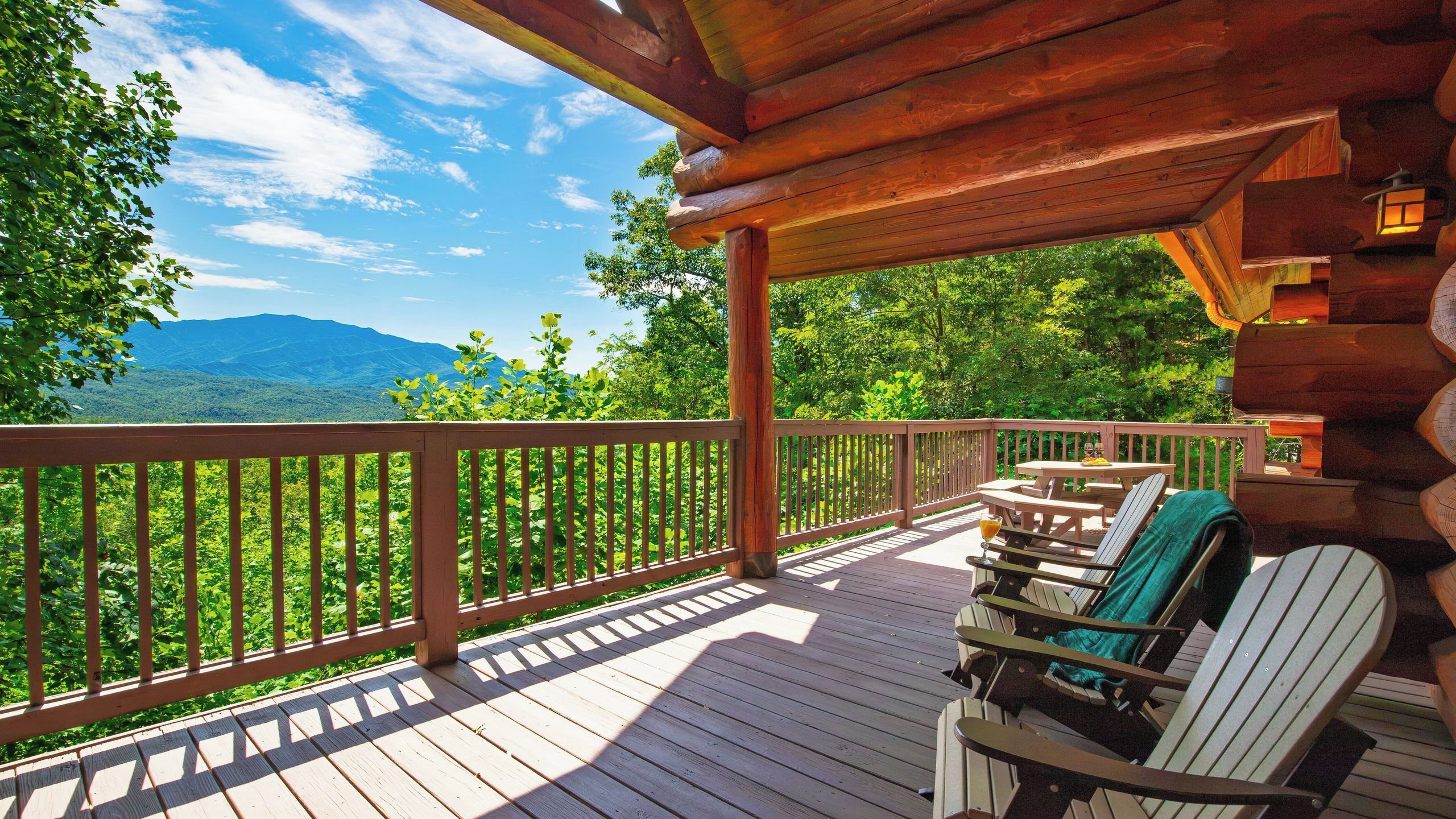 A wooden deck with outdoor seating and a view of a mountainous landscape.