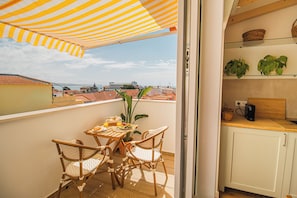 A balcony with a table set for breakfast, wicker chairs, and a striped umbrella. - 188 Apartments - Orquídea (City Center and Ocean View) (Cascais)