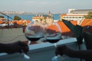 Udsigt fra et vindue over et kystlandskab med bygninger og havet.