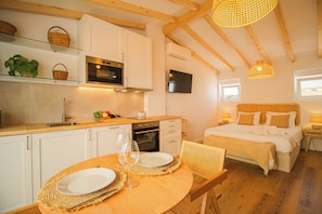 A modern kitchen with white cabinets, a wooden countertop, and a dining area with a round table set for two. - 188 Apartments - Orquídea (City Center and Ocean View) (Cascais)