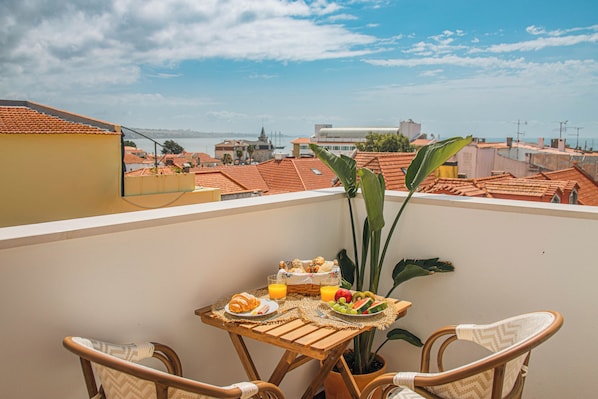 A balcony with a table set for breakfast, overlooking a cityscape with red-roofed buildings. - 188 Apartments - Orquídea (City Center and Ocean View) (Cascais)