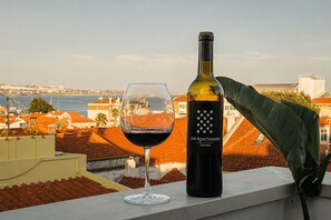 A bottle of wine and a glass on a balcony with a view of a coastal town. - 188 Apartments - Orquídea (City Center and Ocean View) (Cascais)