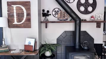Een gezellige kamer met een open haard, een houten bord met een grote letter D, en decoratieve spullen op planken.