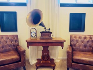 A room with a vintage gramophone on a wooden table, flanked by two leather armchairs.