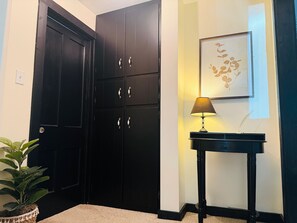 A corner with a black door, a small table with a lamp, and a framed picture on the wall.