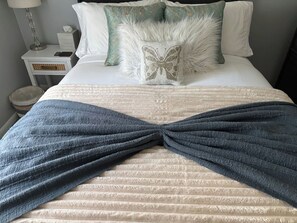 A bed with a decorative bow pillow, a white pillow, and a teal pillow with a leaf pattern. - Historic Charm 2BR Home with Library + Sunset View (Uniontown)