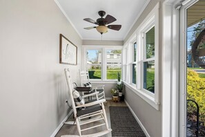 A narrow hallway with a ceiling fan, a window with a view of the outdoors, and a door leading to another room. - Historic Charm 2BR Home with Library + Sunset View (Uniontown)