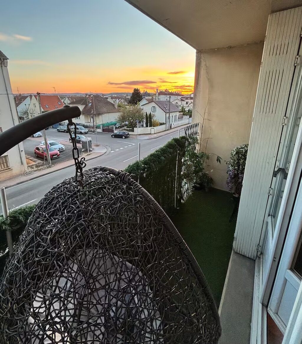 A balcony with a view of a street and buildings during sunset.