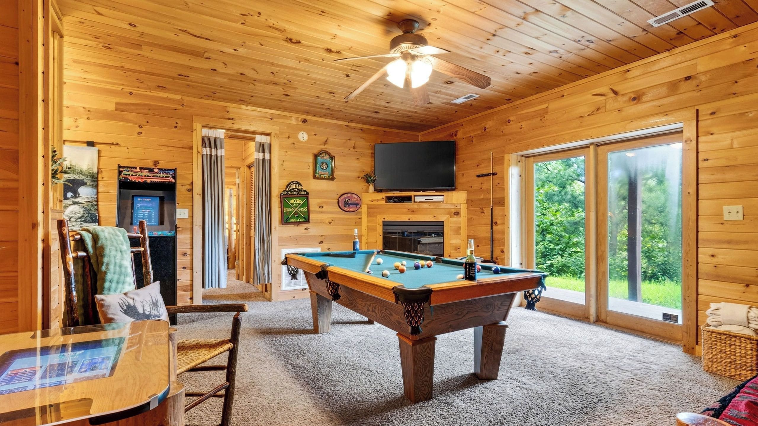 Een houten interieur met een pooltafel, een televisie en een deur naar buiten.