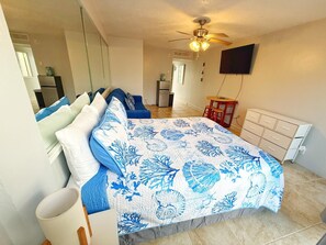 A bedroom with a bed, a ceiling fan, a TV, and a dresser. - NEW Amazing Ocean View Studio in Daytona Beach! (Daytona Beach)