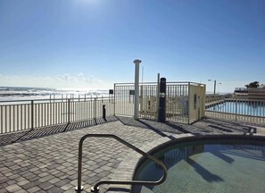 A swimming pool with a metal railing, a small building, and a view of the ocean. - NEW Amazing Ocean View Studio in Daytona Beach! (Daytona Beach)