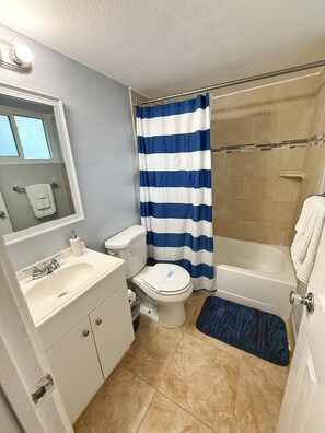 Ein Badezimmer mit Toilette, Waschbecken, Badewanne und Duschvorhang.