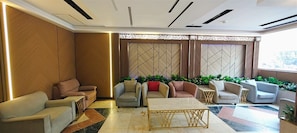 A modern lounge area with sofas, a coffee table, and decorative plants. - Maather Elite Hotel (Makkah)