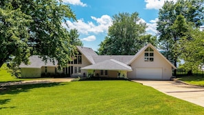 A two-story house with a garage, surrounded by a well-maintained lawn and trees. - The Ranch of Monkey Island [Private Dock] (Afton)