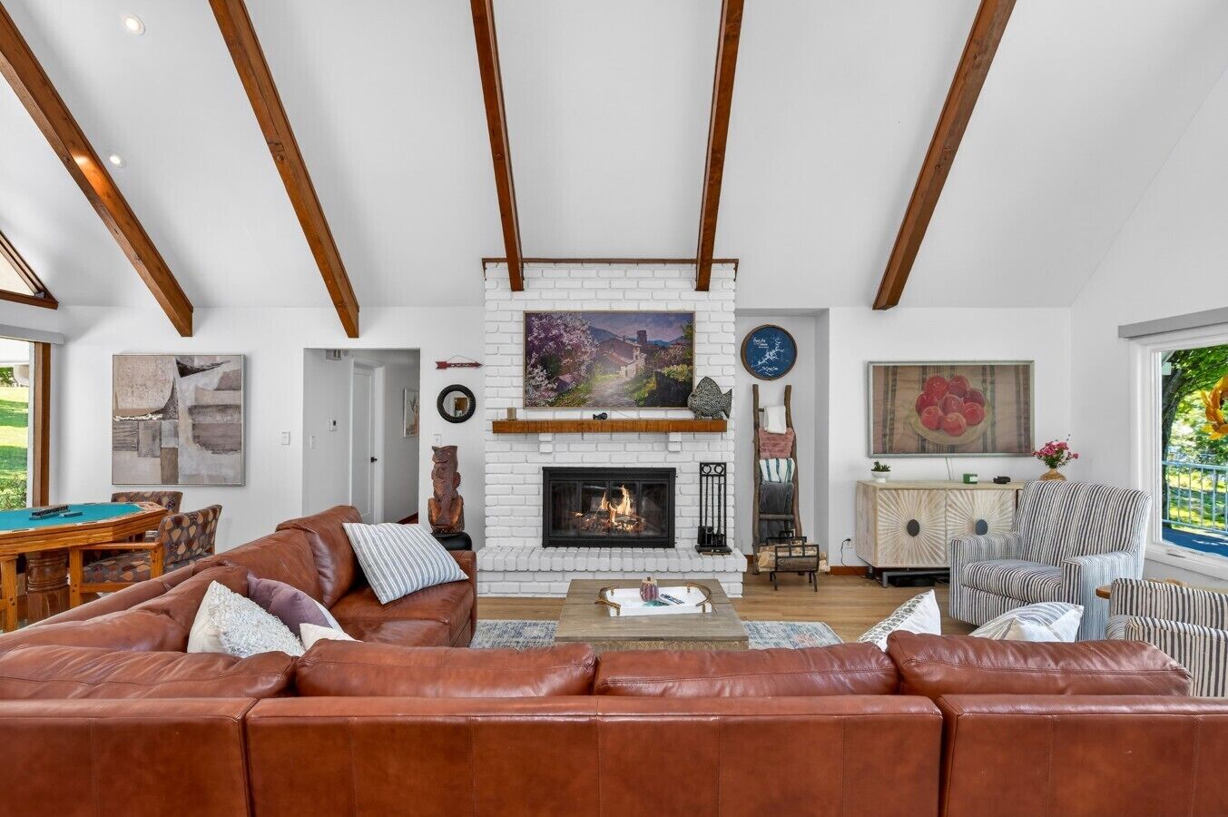 A spacious living room with a fireplace, a pool table, and a large window.