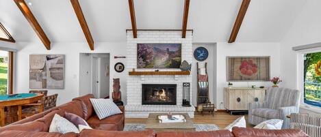 A spacious living room with a fireplace, a pool table, and a large window.