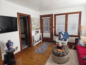 A living room with a TV, a sofa, a coffee table, and a door leading to another room. - Perfect 2-bedroom house, walk downtown Appleton or Packer stadium 30 min drive (Appleton)