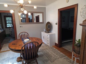 A dining area with a wooden table, chairs, a chandelier, a mirror, and a cabinet. - Perfect 2-bedroom house, walk downtown Appleton or Packer stadium 30 min drive (Appleton)