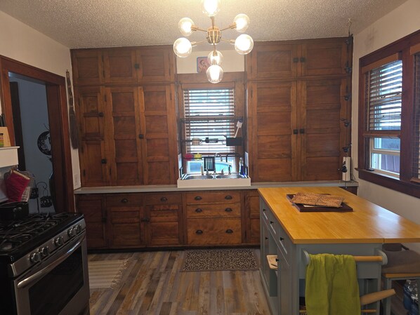 A kitchen with wooden cabinets, a stove, a sink, and a window with blinds. - Perfect 2-bedroom house, walk downtown Appleton or Packer stadium 30 min drive (Appleton)
